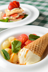 Vanilla ice cream in a cone served with melon and watermelon ice cream scoops in a white plate.
