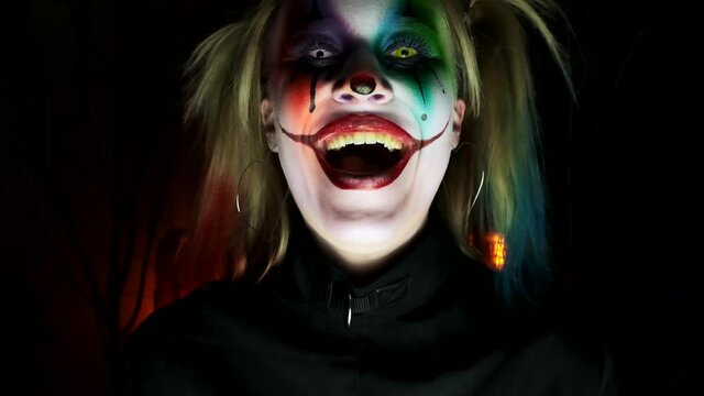 Young actress in makeup clown Halloween laughs madly camera dolly close-up slow motion