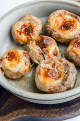 Georgian traditional dish Stuffed mushrooms served in a bowl with a lot of fresh greenery on rustic wooden table.