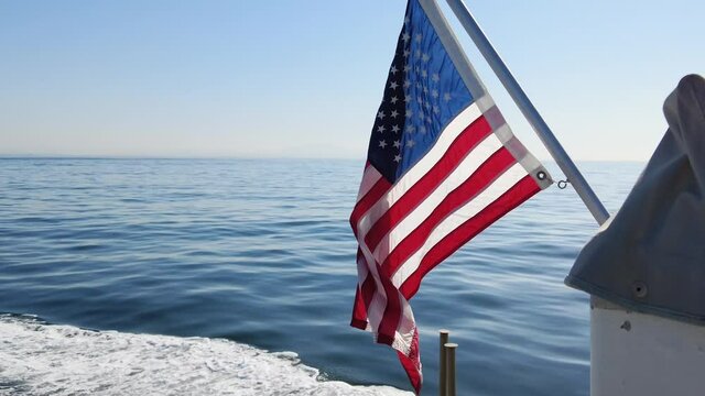 American Flag Waves Gently On The Back Of Moving Boat over the Pacific Ocean