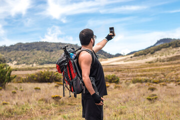 Young adult tourist taking a selfie with his cell phone in the warm savanna of Chirripo National Park in Costa Rica