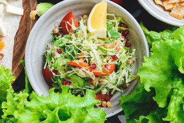 Georgian salad with onions and vegetables served in a bowl with a lot of fresh greens around.