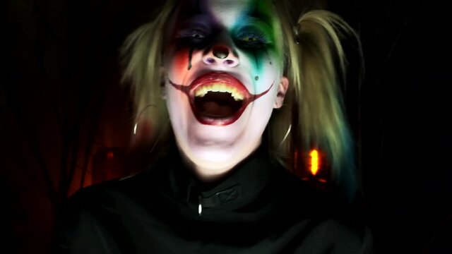 model crazy clown on Halloween laughs terribly at the camera and approaches close-up slow motion