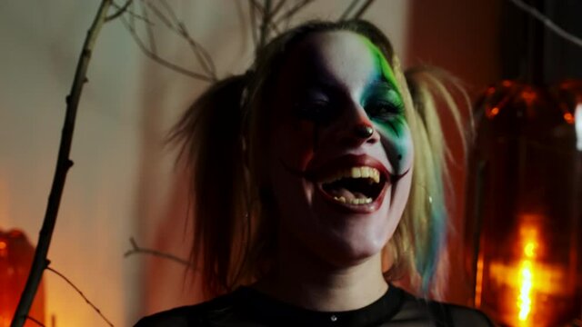 actress in makeup crazy clown laughs and looks into the camera at Halloween close-up slow motion