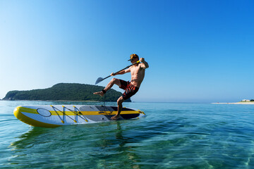 Tanned sportsman falling to sea water practicing supsurfing with paddle extreme sport leisure