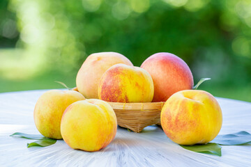 Yellow Peach with sliced on the wooden table over blurred greenery background, Fresh peach on wooden basket in wooden Background.