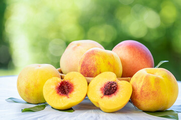 Yellow Peach with sliced on the wooden table over blurred greenery background, Fresh peach on wooden plate in wooden Background.
