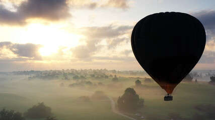 Hot Air Balloon above forest and sun flares, aerial
Drone view over green field with trees and mist at sunset
