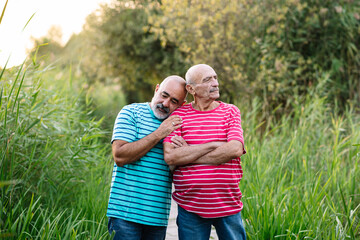 Tender middle-age gay couple in love spending time together while enjoying an outdoor date in a park. LGBT couple concept.