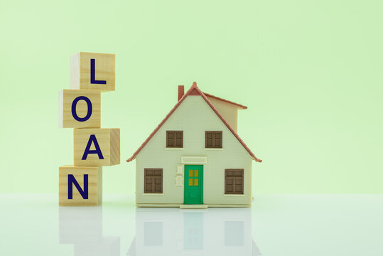 Home equity loan, mortgage loan, financial concept : House model, wood cubes with a word loan on a table over light green background, depict borrowing or lending money to buy or purchase real estate