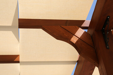 summer ceiling of wooden beams and white fabric and blue sky