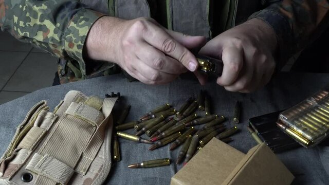 Male hands loading a rifle magazine with bullets. Hands  insert live ammunition into an assault rifle magazine