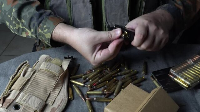 Male hands loading a rifle magazine with bullets. Hands  insert live ammunition into an assault rifle magazine
