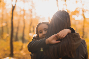 Mother and daughter spend time together in autumn yellow park. Season and single parent concept.
