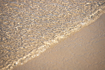 The influx of water in a thin layer on the sandy shore.