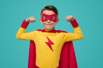 Proud superhero kid in mask showing biceps