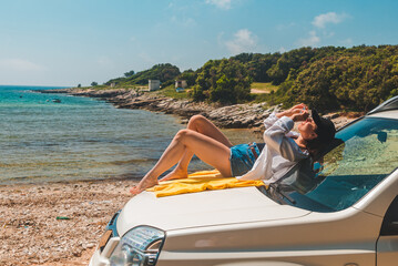 Obraz premium happy woman at sea summer beach sitting at car hood