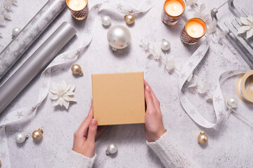 A woman holds gift box among silvery and white jewelry. Preparing for Christmas and New Years.