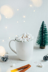 close-up of a white cup with a drink and marshmallows against the backdrop of christmas decor on a white background