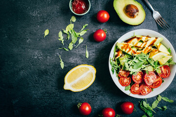 top view of tomato salad arugula avocado lemon in white plate on black background