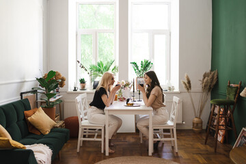Mom, I can share everything with you. Mother and her daughter are sitting in the kitchen having a cup of tea and talking.