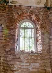 Fototapeta na wymiar old arched windows in an abandoned church, iron grilles in front of the windows, crumbling window sills and window sills