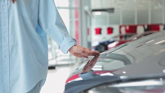Close up cropped video adult woman customer female buyer client wears classic shirt chooses touches auto wants to buy new automobile in car showroom vehicle salon dealership store motor show indoor