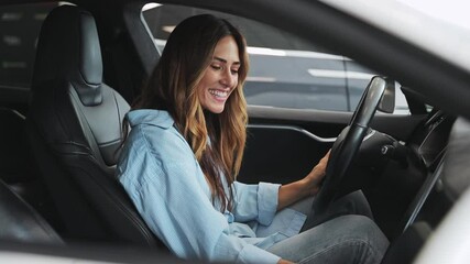 Happy adult woman customer female buyer businesswoman client wears classic shirt sit in saloon look around wants to buy new automobile in car showroom vehicle salon dealership store motor show indoor