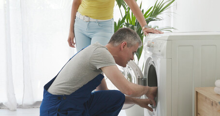 Technician repairing a washing machine at home