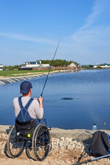 fisherman in wheelchair threw spinning rod into a pond, active recreation for people with disabilities, disabled angler