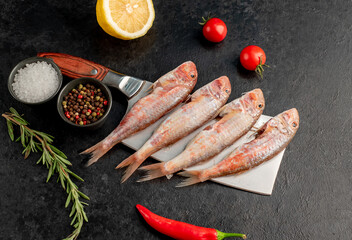 raw red mullet fish on a knife on stone background