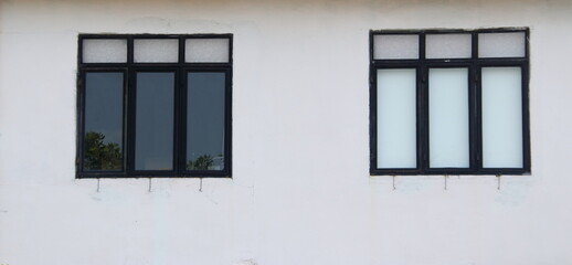 Fototapeta premium Triple mirror window in painted black aluminium frame on white painted wall of building.