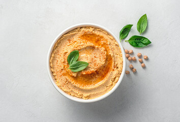 Hummus with olive oil, spices and basil on a light gray background. Vegetable, oriental dish.