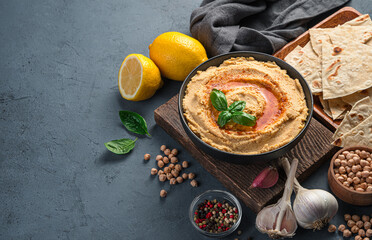 Hummus with olive oil and paprika on the background of ingredients. An oriental, traditional snack. Vegetarian food.