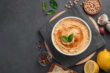 Hummus with olive oil and spices on a dark background with ingredients. Top view, copy space.