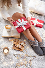 Cozy Woman legs with christmas socks and gifts.