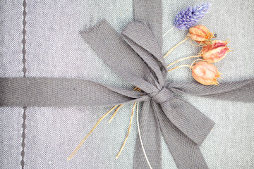 Close up cute grey ribbon bow on a grey linnen package. High quality photo