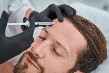 Male patient receiving a subcutaneous injection into his forehead