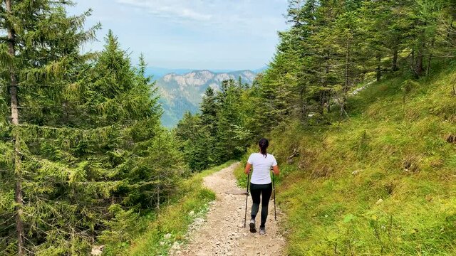 Female hiker in the Alps of Allg&auml;u Bavaria Germany with hiking ploes with mountain panorama in the background, Hochalp close to Pfronten