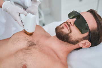 Beauty salon customer undergoing a laser chest hair removal - obrazy, fototapety, plakaty