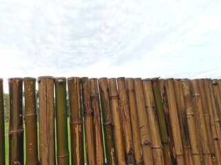Obraz premium Strong bamboo fence against clouds in the sky