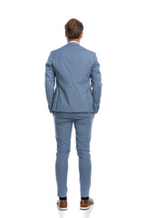 rear view of elegant businessman in blue suit holding hands in pockets