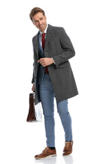 sexy young businessman with gray coat and suitcase looking to side