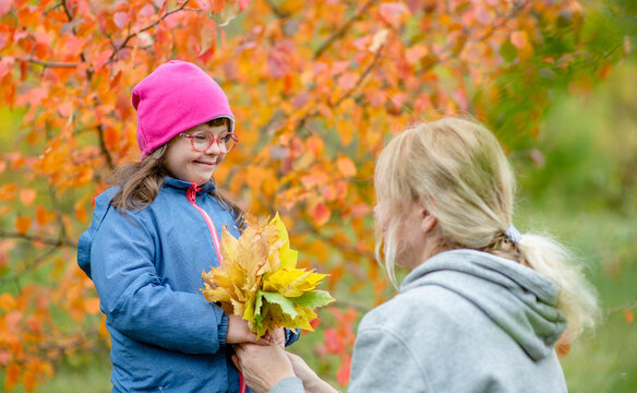 Mother and little girl with special needs have a fun in autumn park