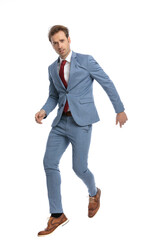 attractive young man in blue suit jumping in the air