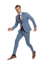 elegant young businessman in blue suit holding arms in fashion pose