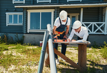 Worker in overalls putting spirit level on drawings