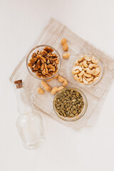 Nuts and vinegar on a linen tea towel on a white table. Walnuts, cashews and pumpkin seeds for proper nutrition. healthy foods and nutrients for the brain and body