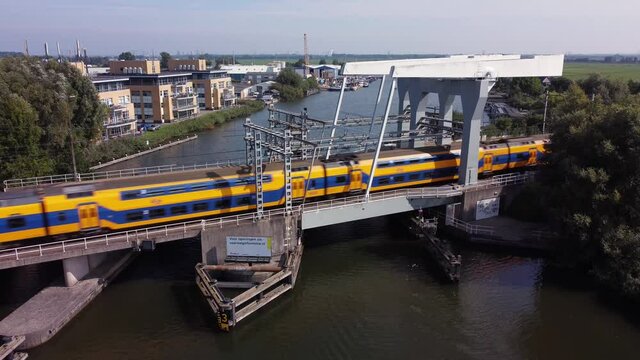 Railway bridge over river Vecht in Holland in the city of Weesp, Dutch yellow train passing
