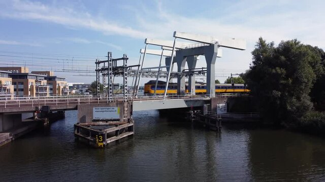 Railway bridge over river Vecht in Holland in the city of Weesp, Dutch yellow train passing